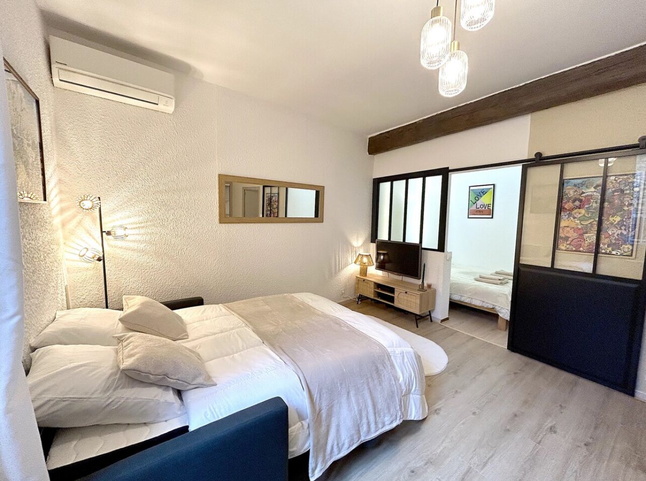 A bedroom with a large bed, a TV, a small table, and a mirror.