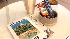 A room with a white round table, a vase with flowers, a bowl with snacks, and a travel guide on the table. - Le Cosy Nîmois, charm & terrace in the heart of Nîmes, 4 minutes from the arena (Nîmes)