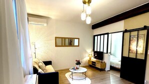 A modern living room with a sofa, coffee table, and a TV. - Le Cosy Nîmois, charm & terrace in the heart of Nîmes, 4 minutes from the arena (Nîmes)