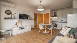 Un soggiorno moderno con divano, televisione e zona pranzo.