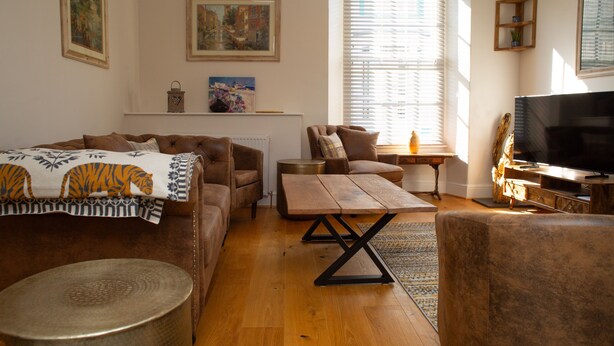 A living room with a sofa, a coffee table, a TV, and a fireplace.