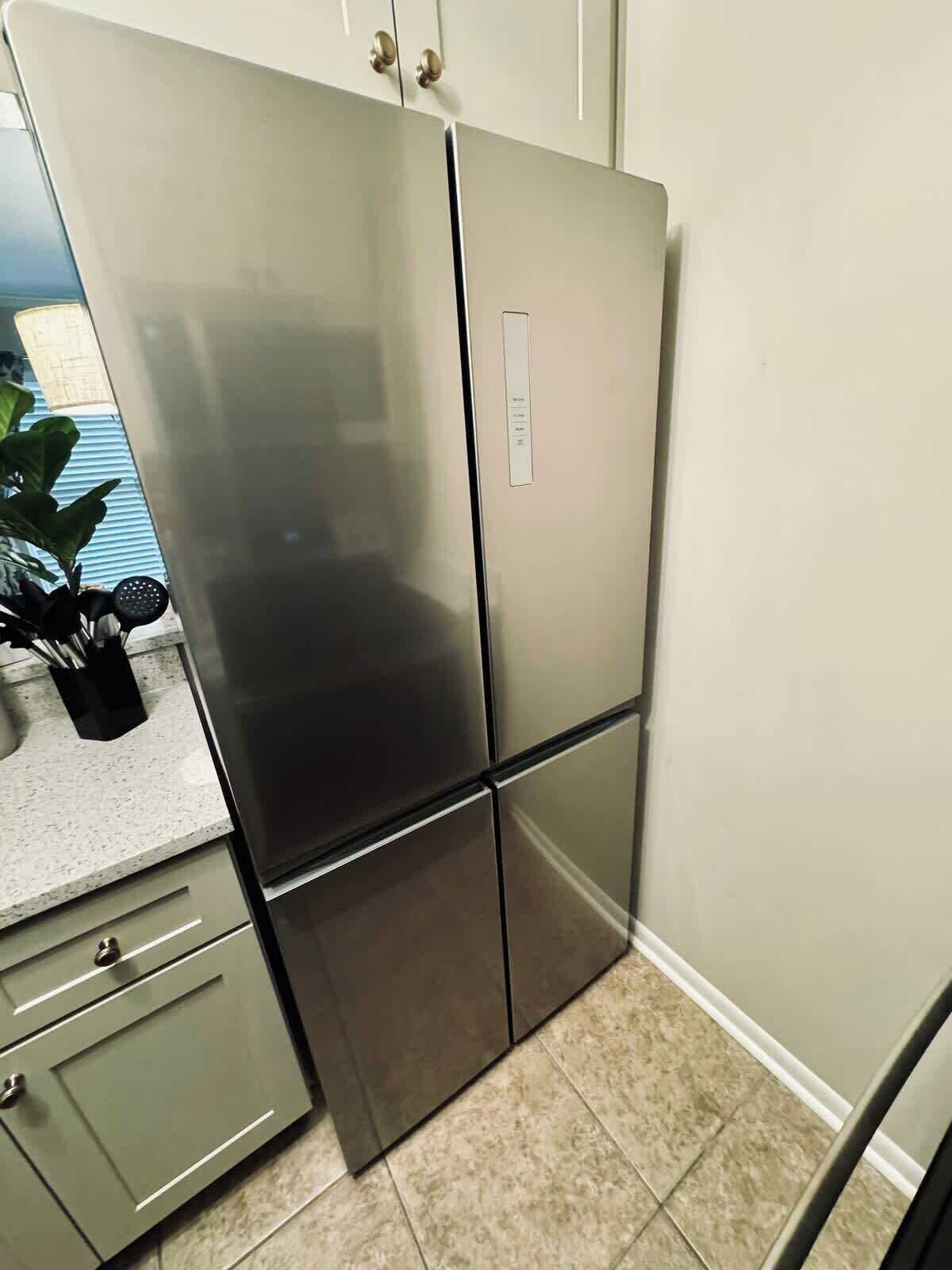 Una cocina con un refrigerador de acero inoxidable, una encimera con una planta y un piso de baldosas.