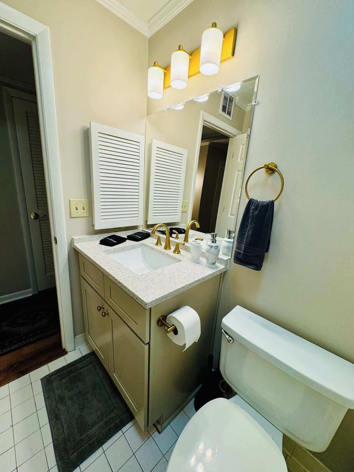 A bathroom with a white sink, two vanity mirrors, a toilet, and a towel ring.