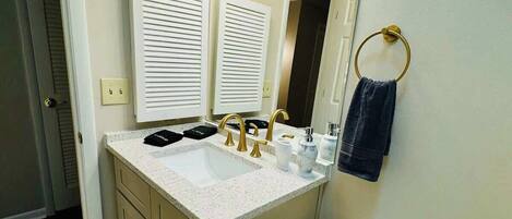 A bathroom with a white sink, two vanity mirrors, a toilet, and a towel ring.