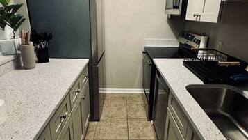 Una cocina estrecha equipada con refrigerador, microondas, estufa y pileta.