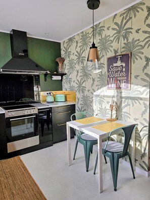 A kitchen with a stove, oven, and a dining area with chairs and a table.