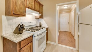 Una cocina con armarios de madera, una estufa blanca y una encimera con un bloque de cuchillos.