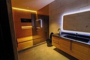 A modern bathroom with a wooden vanity, a glass shower enclosure, and a built-in sink. - Gey Tropical House (Liberia)