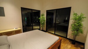 Ein Schlafzimmer mit Bett, Nachttisch, Blumentopf und einer Glasschiebetür, die auf einen Balkon führt.