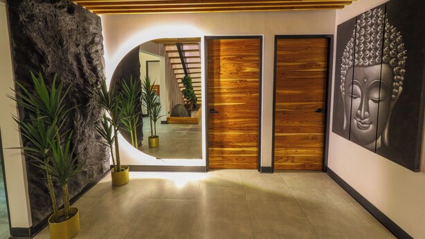 Ein modernes Interieur mit Holzboden, einer großen Steinwand und einem Buddha-Gemälde.