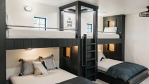 Une chambre avec un lit superposé, un panneau indiquant « ZONE DE SILENCE », une échelle et une fenêtre avec des bordures bleues.
