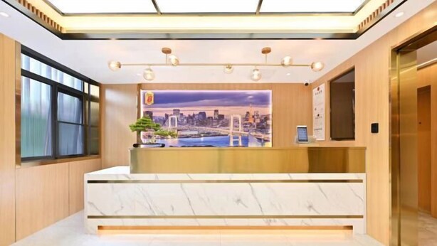 Zona de recepción de hotel con un mostrador de mármol, un mural con vistas a la ciudad y un ascensor moderno.