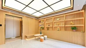 Un moderno vestíbulo de hotel con techos altos, una zona de estar central y una pared de estanterías con diversos objetos decorativos.