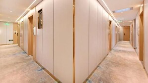 Un pasillo de hotel con piso alfombrado, paneles de madera y luces empotradas.