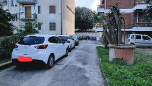 Una calle residencial con coches aparcados, una tapa de alcantarilla y edificios de varios pisos con balcones.