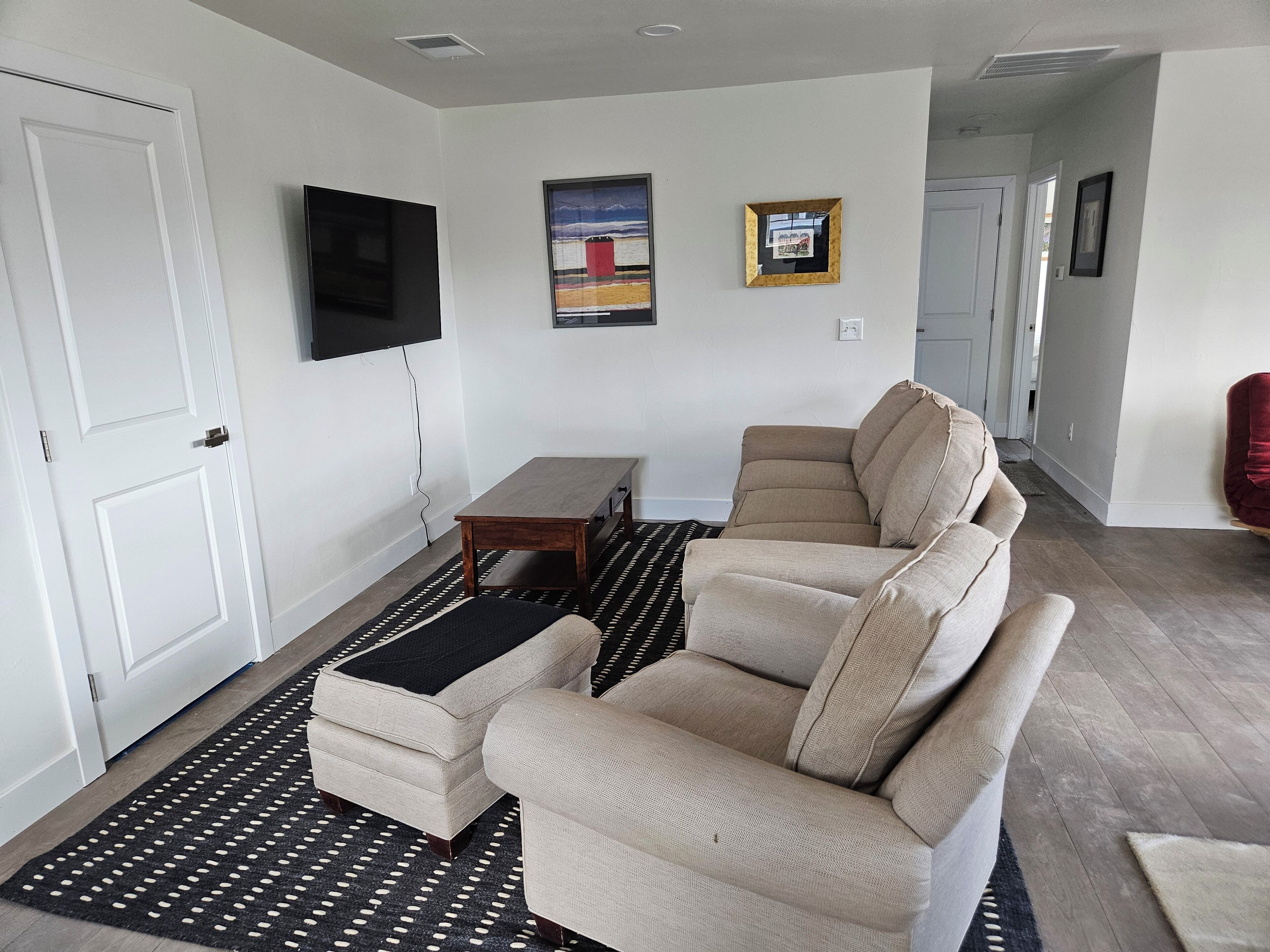 A living room with a beige sofa, a small wooden table, and a black and white patterned rug.