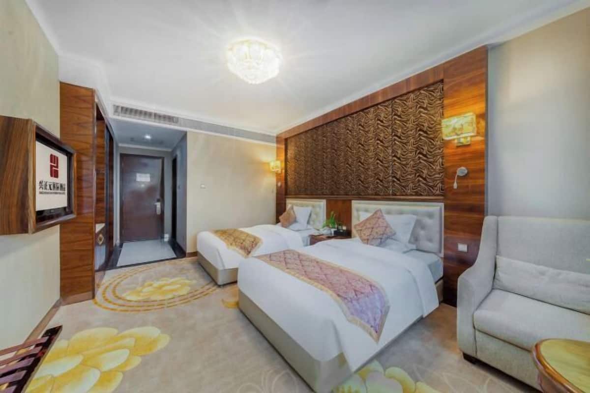A hotel room with two beds, a sofa, a TV, and a decorative wall panel.