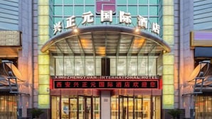El exterior del Hotel Internacional Xing Zhengyuan, con una entrada destacada y señalización en varios idiomas.