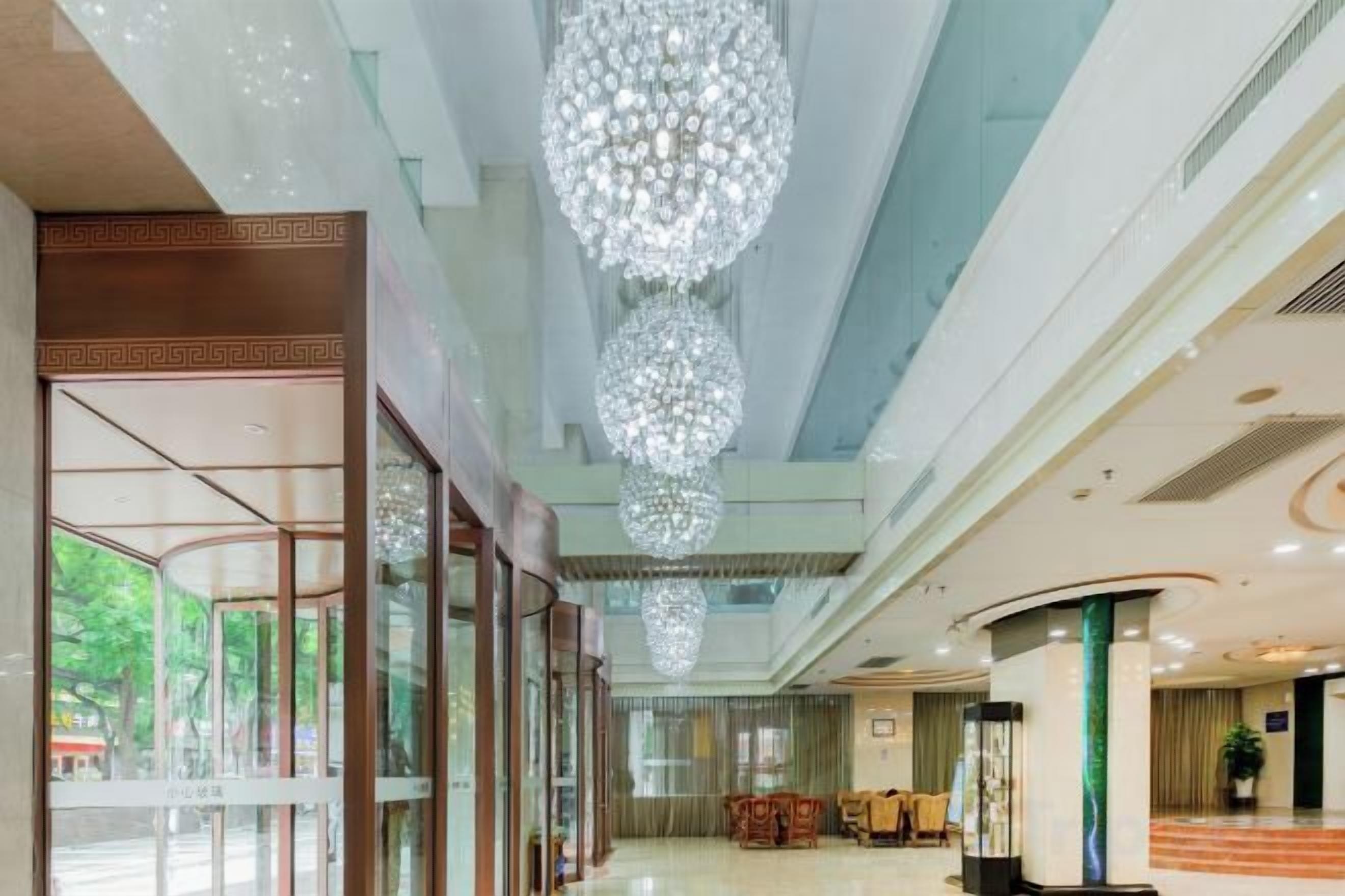 A spacious lobby with a high ceiling, large chandeliers, and a glass entrance.
