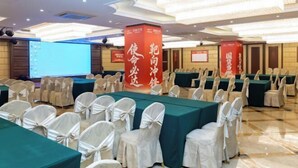 A conference room with rows of tables and chairs, large banners with text, and a projection screen. - Xingzhengyuan International Hotel (Xi'an)
