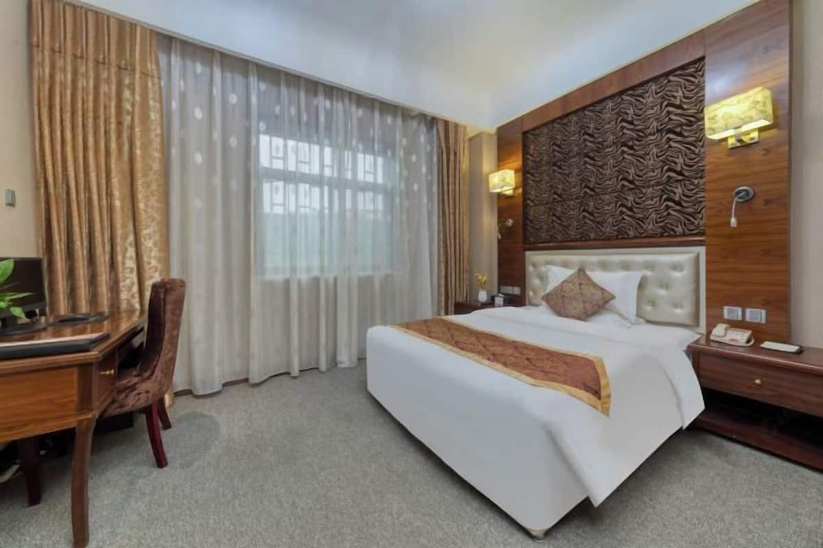A hotel room with a large bed, a desk, and a chair.