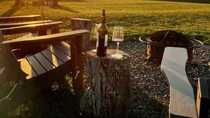 Een zonsondergang uitzicht met terras, een fles wijn en een glas op een boomstronk.