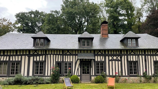 Un bâtiment de style Tudor, doté d’un toit à forte pente, de nombreuses cheminées et d’une façade symétrique avec des fenêtres régulièrement espacées.