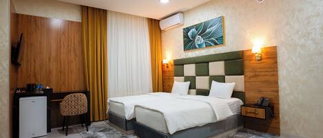 Habitación de hotel con dos camas, un escritorio, una silla, un televisor y un cuadro en la pared.