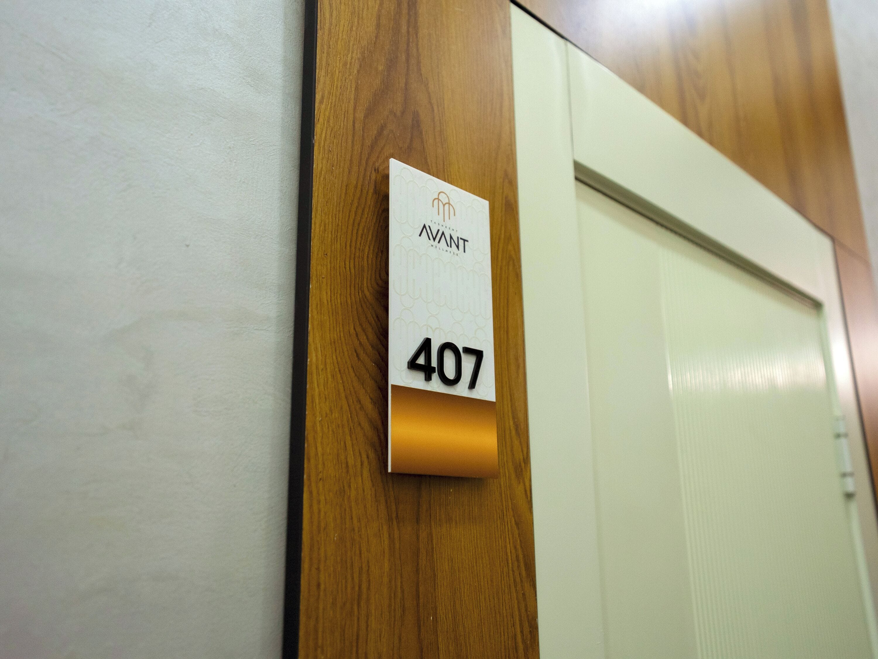 A hotel room door with a wooden panel and a white sign with the number 407.