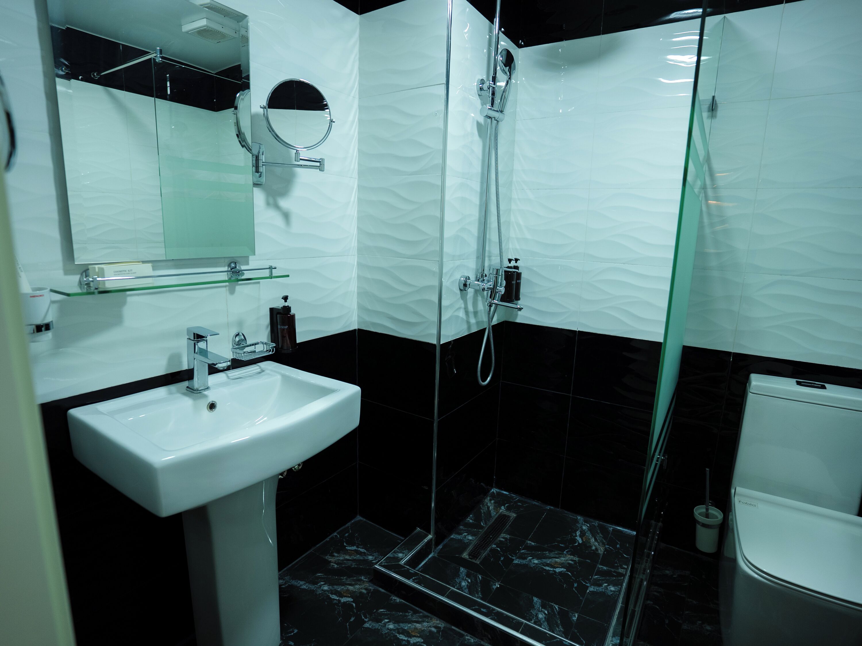 A modern bathroom with a white sink, a glass shower enclosure, and a toilet.
