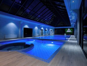 A modern indoor swimming pool with a glass ceiling, a jacuzzi, and a sign for 'AVANT Swimming Pool'. - Avant Wellness Hotel Tashkent Pool&Spa (Tashkent)