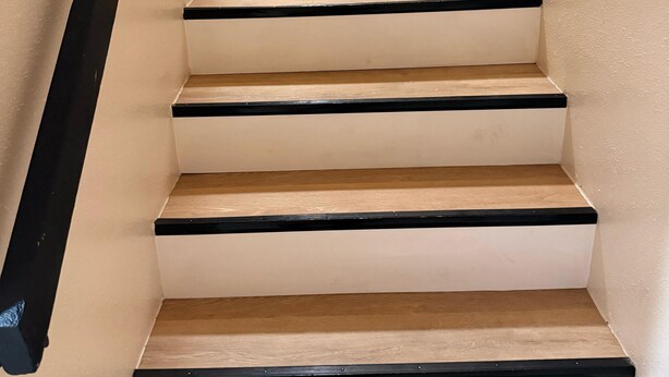 A staircase with beige walls and black railings. - Toria Suites 922 (Lakeland)