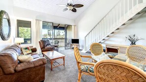 A spacious living room with a ceiling fan, comfortable seating, a television, and a view of the outdoors. - Charming 1-bedroom condo in awesome Kuilima, Kahuku, Oahu (Kahuku)