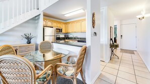 Una cocina moderna con armarios de madera, una mesa de comedor de vidrio y sillas de mimbre.