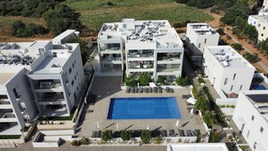 Ein modernes, mehrgeschossiges Gebäude mit Pool auf dem Dach, Außenbereich zum Sitzen und Solaranlage.