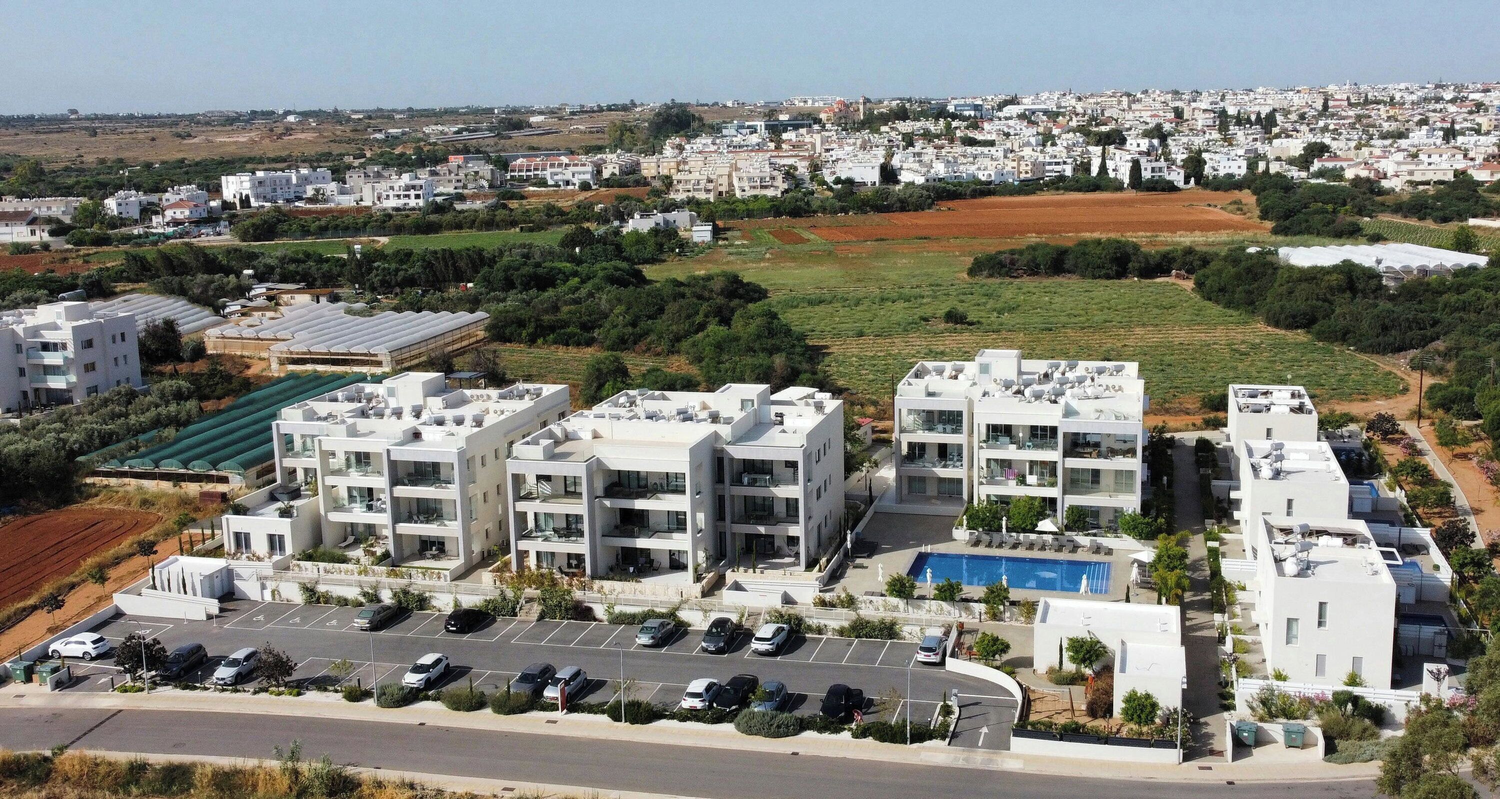 Un quartier résidentiel avec des immeubles d’appartements modernes, une piscine et un parking.