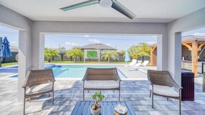 Une terrasse couverte avec deux fauteuils en osier, une table ornée d’une plante en pot et un ventilateur de plafond.