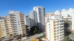 Ein hoch aufragendes Wohngebäude mit mehreren Balkonen, einem zentralen Innenhof und einem strahlend blauen Himmel.