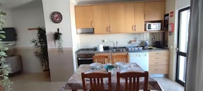 A compact kitchen with wooden cabinets, a microwave, and a dining table set for four. - Apartment 'T2 Edificio Cruzeiro' with Private Pool, Wi-Fi and Air Conditioning (Portimão)