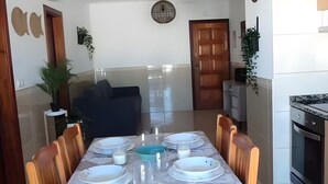 Ein Essbereich mit einem Marmortisch, Holzstühlen, einem Deckenventilator und einer Küche im Hintergrund.