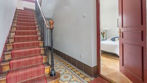 A staircase with red carpeted steps, a wooden handrail, and a patterned floor.