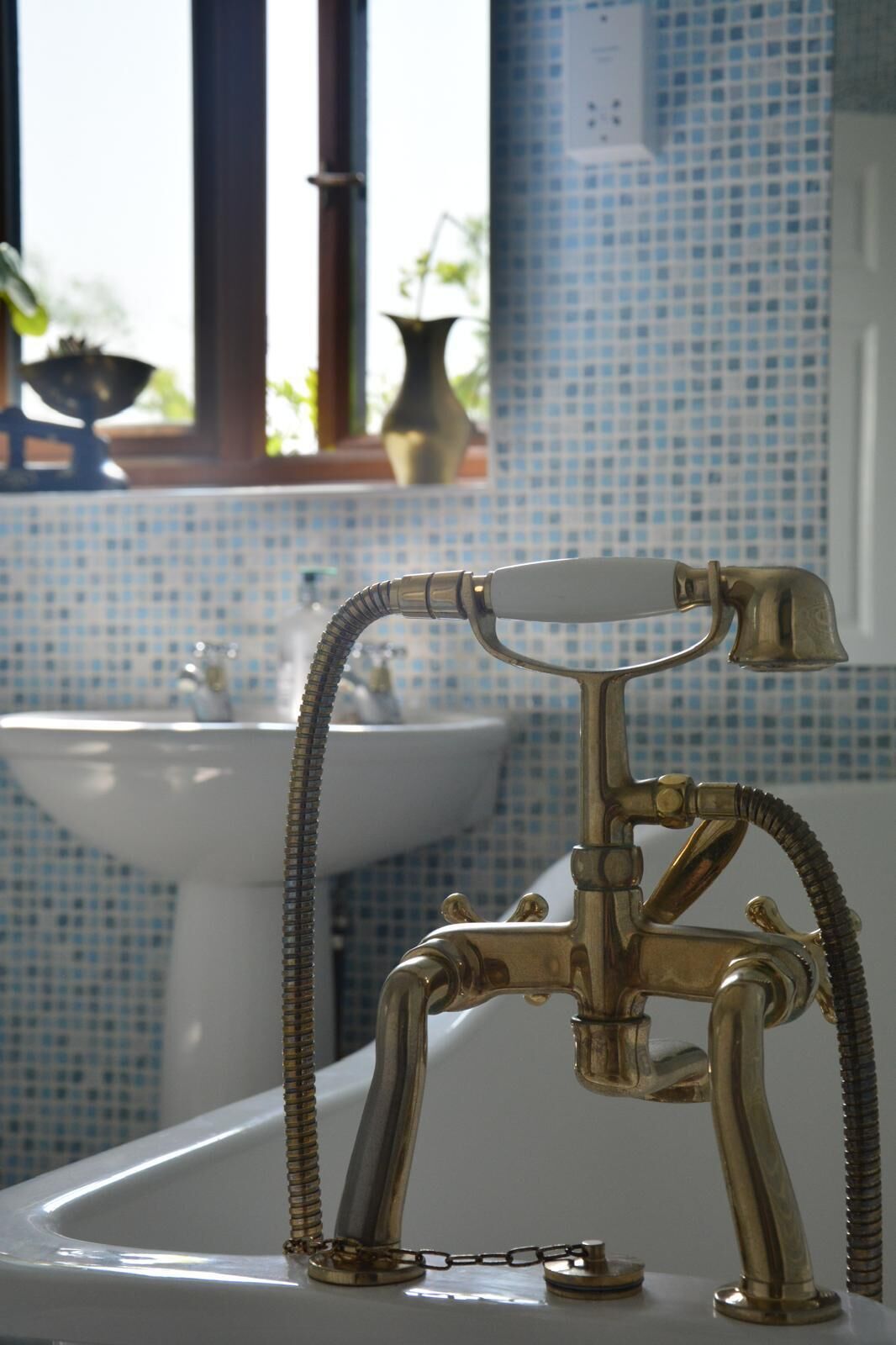 Une salle de bain avec un robinet en laiton d’époque et un lavabo.