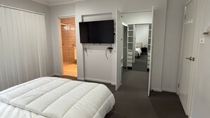 A bedroom with a bed, a TV mounted on the wall, and a closet with a mirror. - Modern Luxury with Nature (Spring Farm)