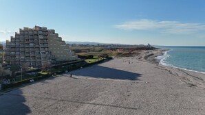 Una playa con un edificio grande, un parque infantil y cielo despejado.