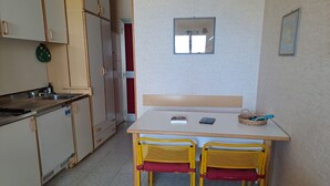 Una cocina pequeña con un lavamanos, estufa y dos sillas junto a una mesa.