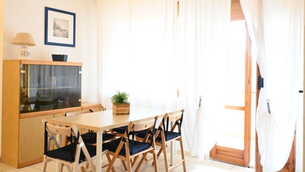 A dining area with a wooden table, four chairs, a cabinet with a glass door, a small potted plant, and a framed picture on the wall. - M422 - Marcelli, three-room apartment with terrace 100m from the sea (Marceli)
