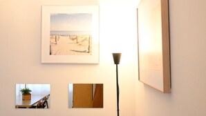 A wall with framed artwork, a floor lamp, and a small table with a plant. - M422 - Marcelli, three-room apartment with terrace 100m from the sea (Marceli)