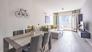 Una sala moderna con comedor, sofás grises, una mesa de centro y una obra de arte con motivo de bicicleta en la pared.