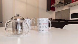 Una zona de cocina con cafetera y una taza sobre la mesa.