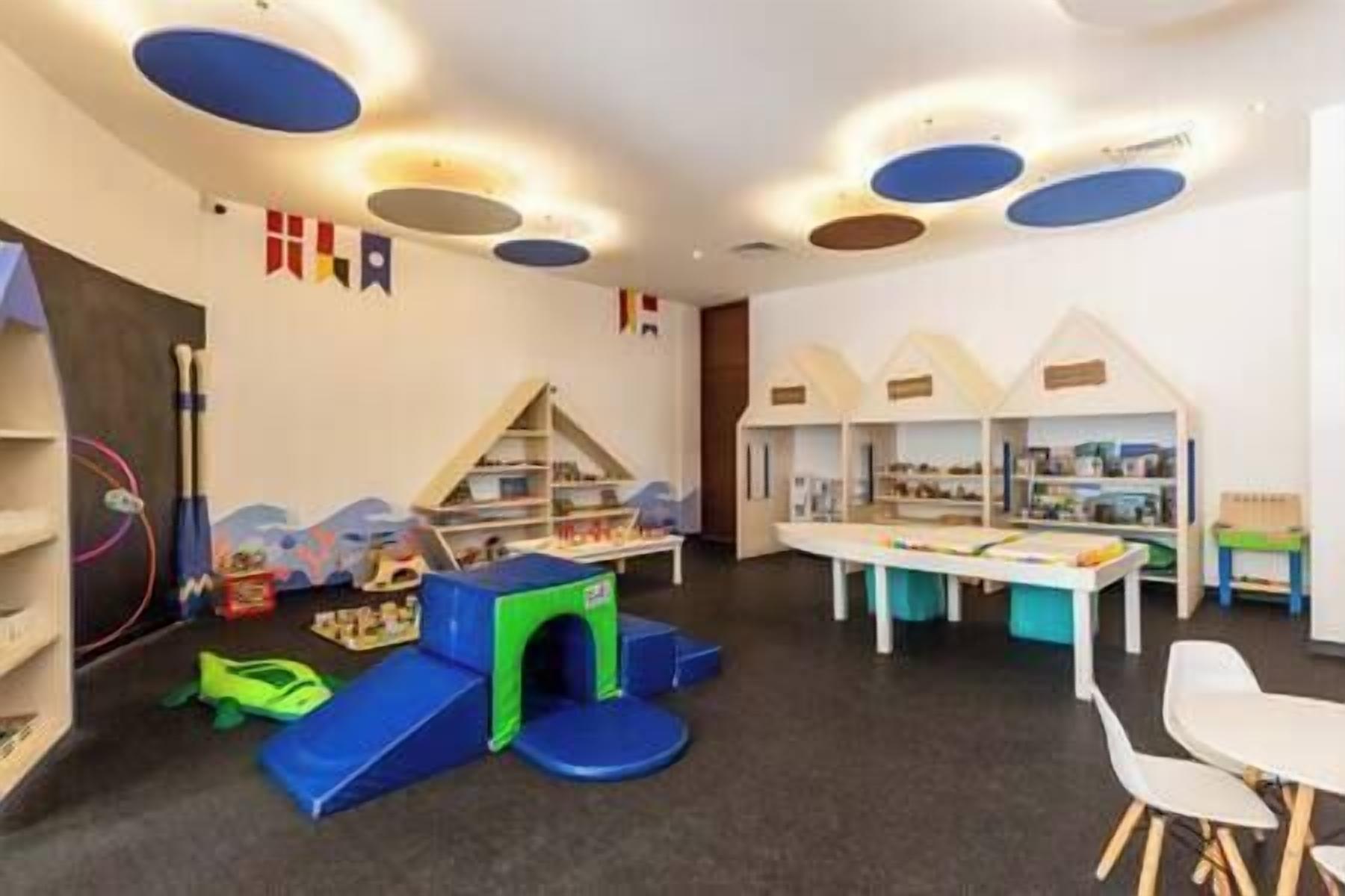 Un espace de jeux pour enfants avec un toboggan, des structures de jeu et une table remplie de jouets.